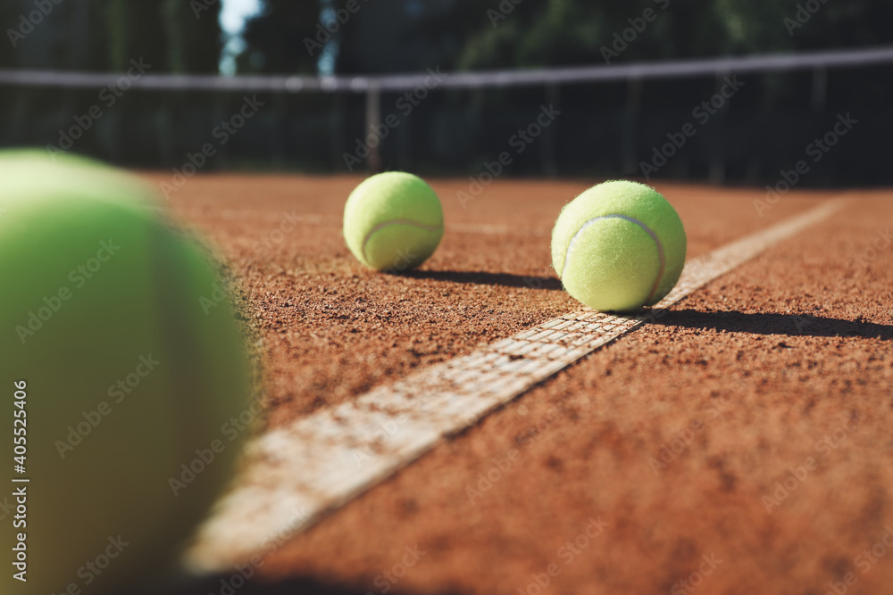 Bright yellow tennis balls on clay court