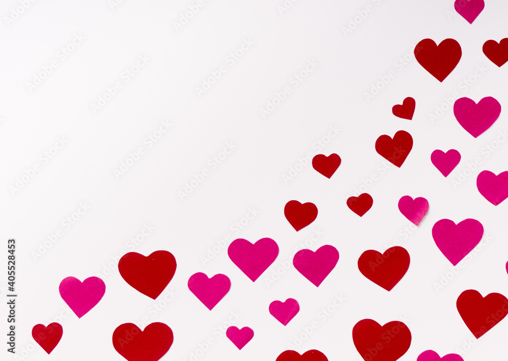 Top view on red and pink paper hearts in corner on white background with copy space