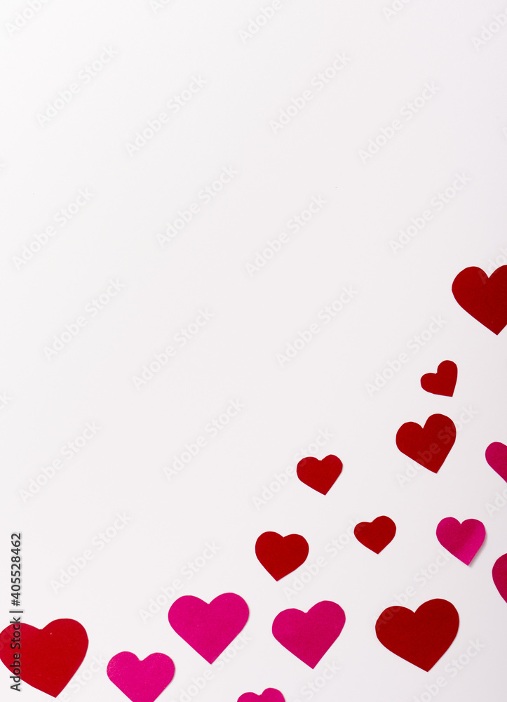 Top view on red and pink paper hearts in corner on white background with copy space