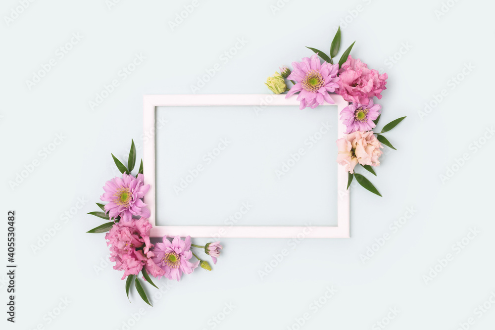 Flower border frame made of pink eustoma on blue pastel background. Greeting card template with copyspace. Nature concept.