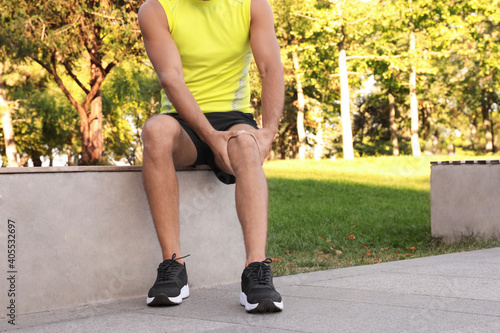 Man in sportswear having knee problems in park, closeup