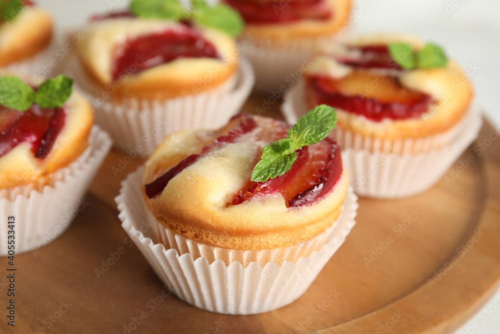 Delicious cupcakes with plums on wooden tray, closeup