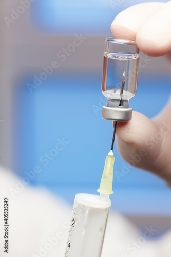 Extreme close-up of syringe and vaccine for covid-19 with fingers in surgical glove