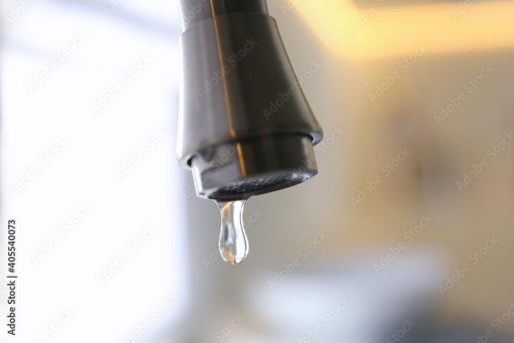 Water drop falling down from tap on blurred background, closeup Water drop falling down from tap on blurred background, closeup