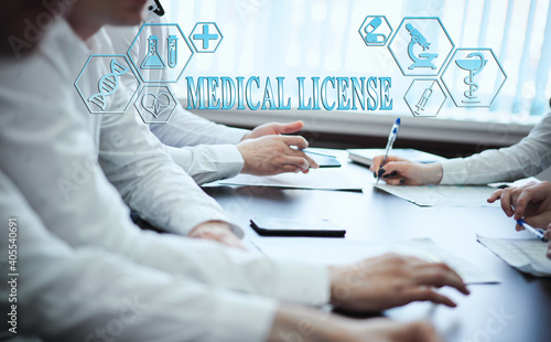 A group of doctors in a modern clinic is planned. The concept of modern medicine and medical biotenology. Medical icons on the screen with the inscription: MEDICAL LICENSE