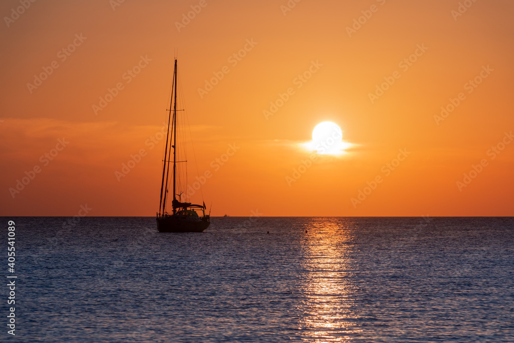 Silhouette of a sailing ship in the ocean at sunset over blue waters