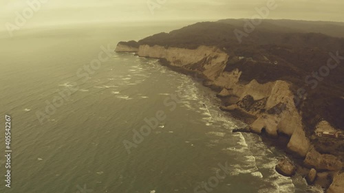 Aerial view of large cliffs seperating the ocean from the mainland with a warm filter put over it photo