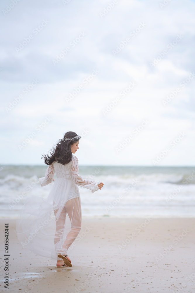 Beautiful women in white dress happily strolling at the beach, beautiful woman dressed in white bride Beautiful women in white dress happily strolling at the beach, beautiful woman dressed in white bride
