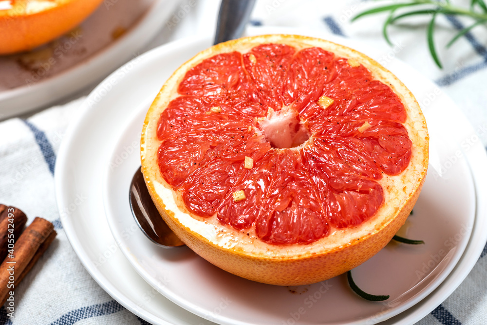 Sweet baked grapefruit with honey, cinnamon, and ginger in a white plate on a served table close-up.