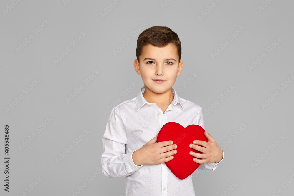valentine's day. cute little child boy holding red heart isolated on gray background valentine's day. cute little child boy holding red heart isolated on gray background