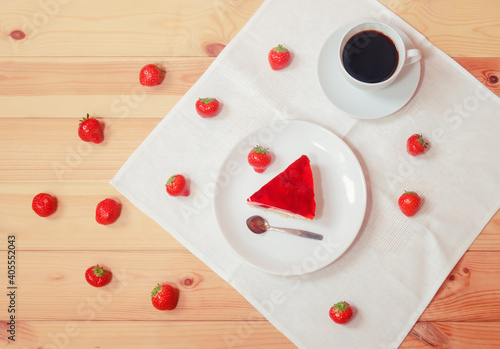 Piece of strawberry cake, cup of coffee and fresh strawberry near on wooden table. Top view.
