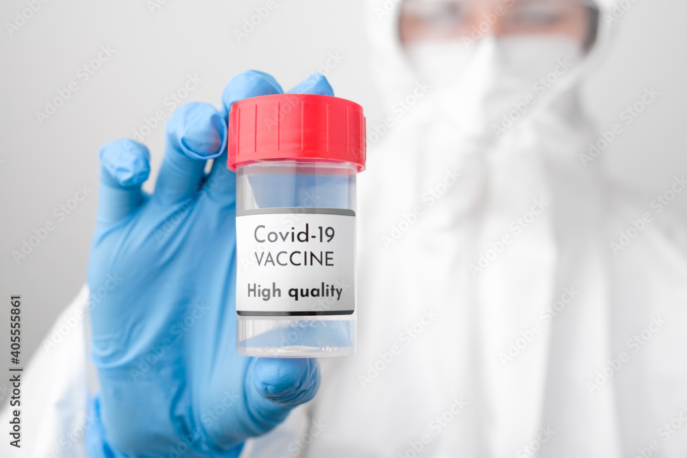 High quality Covid 19 vaccine bottle in doctors hand. Doctor in protective suit, face mask, safety googles and rubber gloves demonstrate vaccine against coronavirus. High quality Covid 19 vaccine bottle in doctors hand. Doctor in protective suit, face mask, safety googles and rubber gloves demonstrate vaccine against coronavirus.