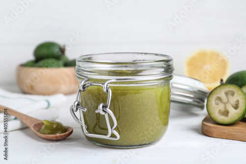Feijoa jam in glass jar on white wooden table, closeup