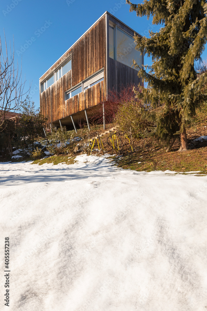 Modern minimal wooden house exterior. The season is winter and therefore you can see the snow in the garden Modern minimal wooden house exterior. The season is winter and therefore you can see the snow in the garden