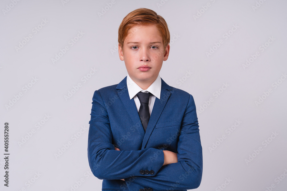 Confident schoolboy with ginger hair with his arms crossed isolated over grey background Confident schoolboy with ginger hair with his arms crossed isolated over grey background