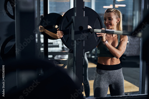 Pleased sportswoman removing a weight plate from a bar