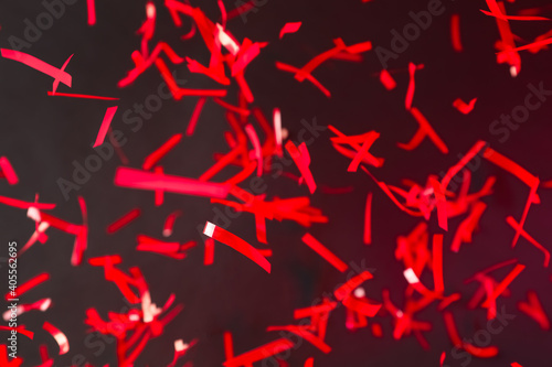 Shiny red confetti falling down on dark background