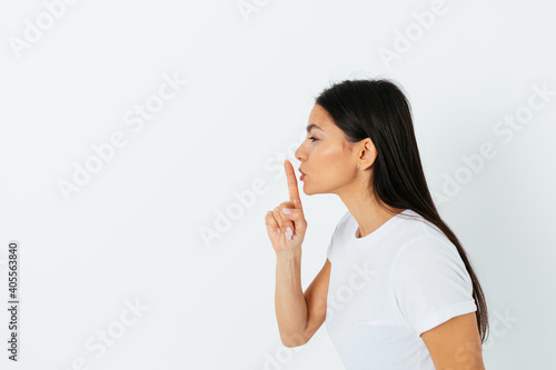 Attractive brunette woman holding index finger near lips photo