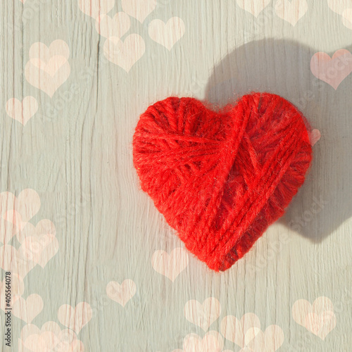 Red heart made of wool threads on a light wooden background. High quality photo
