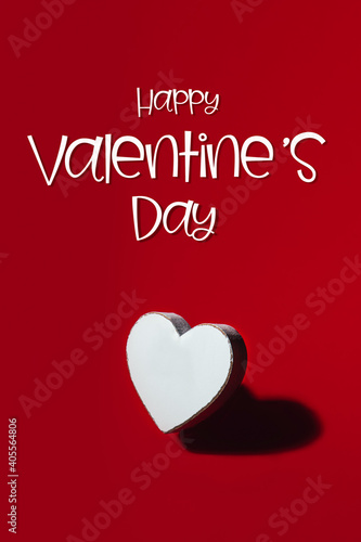 Happy Valentines Day text on card. White wooden heart with strong shadow on red background, as symbol of love and passion, Happy Valentines Day Concept