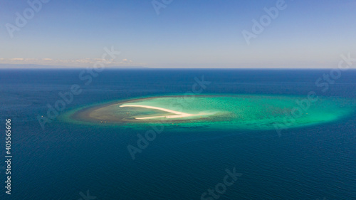 Seascape, white sand island. Atoll near the island of Camiguin, Philippines, aerial view. Atoll with a white island. Beautiful coral reef in the blue sea, top view.