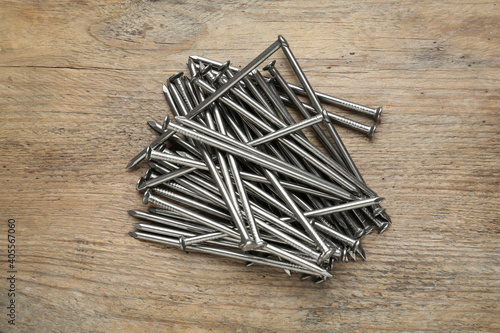 Many metal nails on wooden background, flat lay