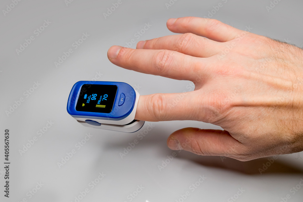 A pulse oximeter on the finger of a man's hand measures the amount of oxygen in the blood and the pulse. A pulse oximeter on the finger of a man's hand measures the amount of oxygen in the blood and the pulse.