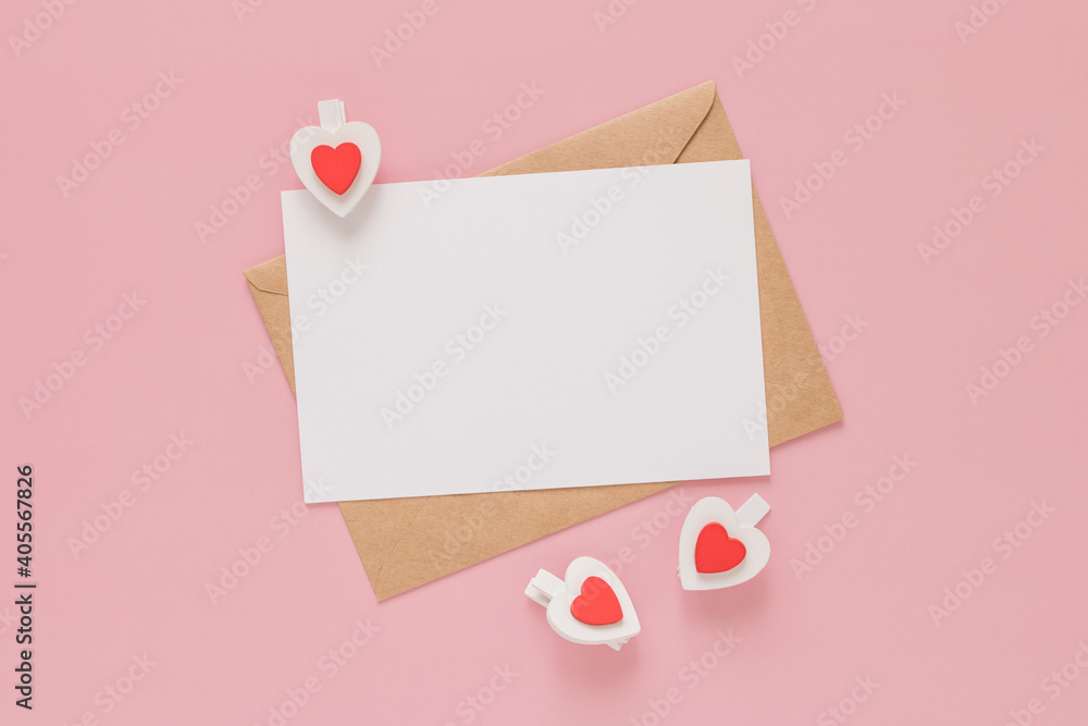 Craft envelopes, white blank sheet of paper and wooden clips hearts on a pink background. Valentine's day concept. Craft envelopes, white blank sheet of paper and wooden clips hearts on a pink background. Valentine's day concept.