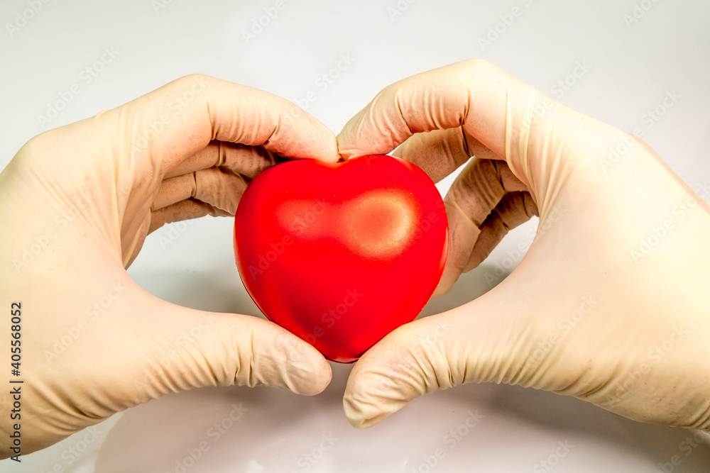 male hands in medical gloves holding a toy red heart male hands in medical gloves holding a toy red heart