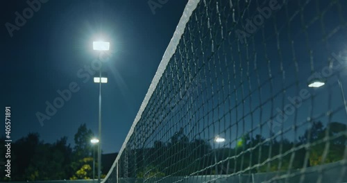 Small yellow ball hits white net surrounded by bright lighting. Close-up shot of central net in tennis circuit. High quality 4k footage photo