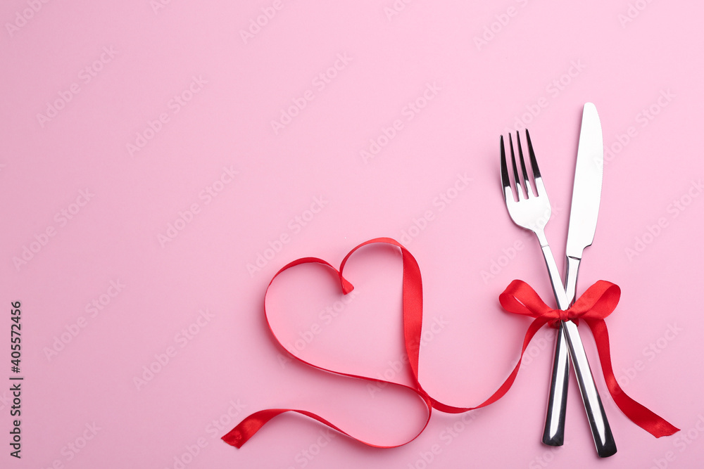 Cutlery set and red ribbon on pink background, flat lay with space for text. Valentine's Day dinner Cutlery set and red ribbon on pink background, flat lay with space for text. Valentine's Day dinner