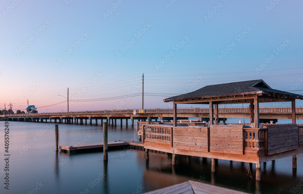 The sun is setting and sky is almost clear of clouds at this Private dock in the Banks Channel near River To The Sea Bikeway bridge in Wrightsville Beach, North Carolina