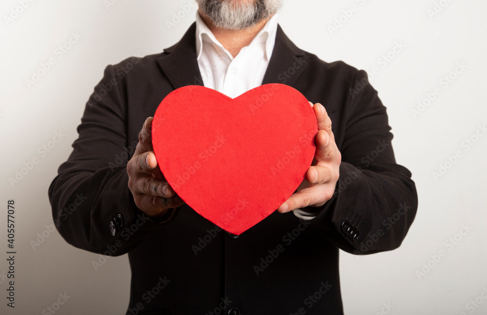 Businessman dressed in suit holding red heart on white background. Valentine's Day with a sweet and romantic moment. Businessman dressed in suit holding red heart on white background. Valentine's Day with a sweet and romantic moment.