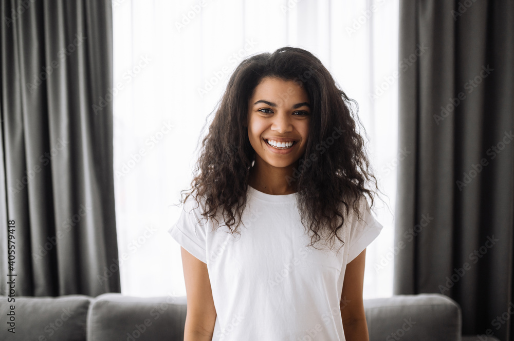 Webcam portrait of smiling african american girl in white t-shirt. Adorable pretty woman on a video conference, looking directly at camera. Profile picture of happy young business lady Webcam portrait of smiling african american girl in white t-shirt. Adorable pretty woman on a video conference, looking directly at camera. Profile picture of happy young business lady