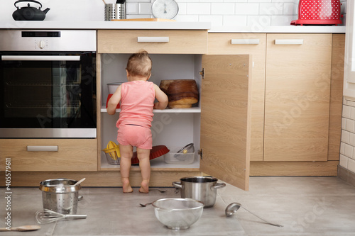Back view of toddler making mess in kitchen cabinet