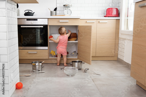 Rear view of toddler making mess in kitchen cabinet