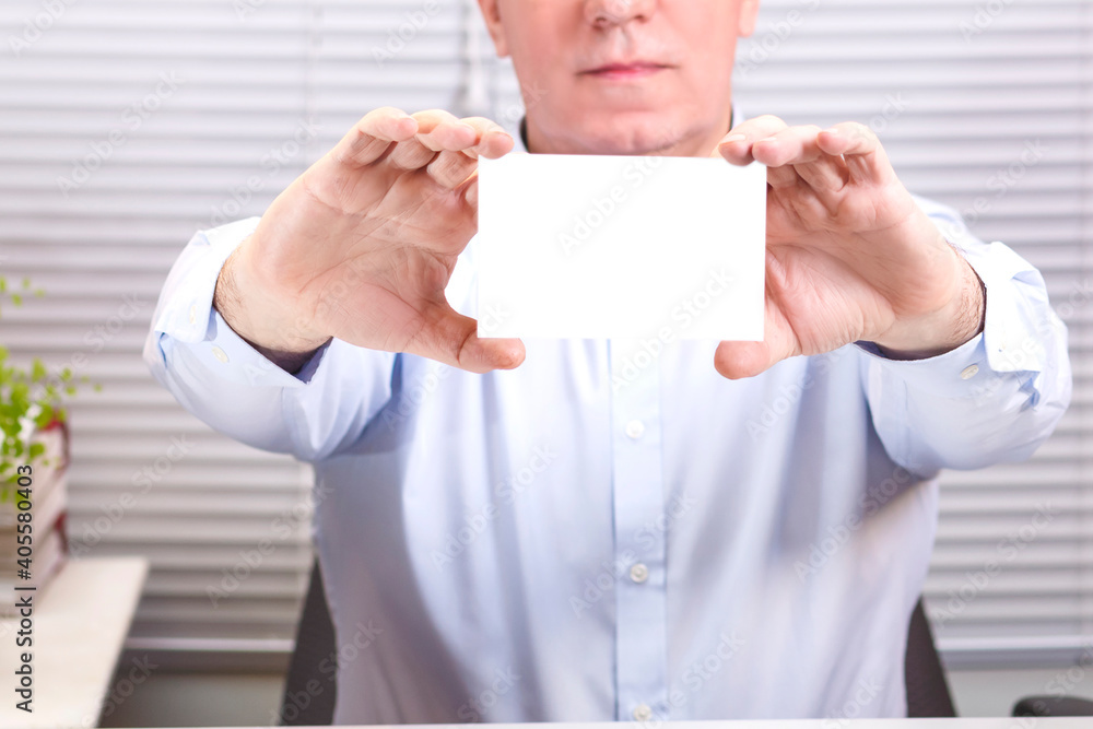 A man in the office at the computer holds a sign in his hands. A man in the office at the computer holds a sign in his hands.