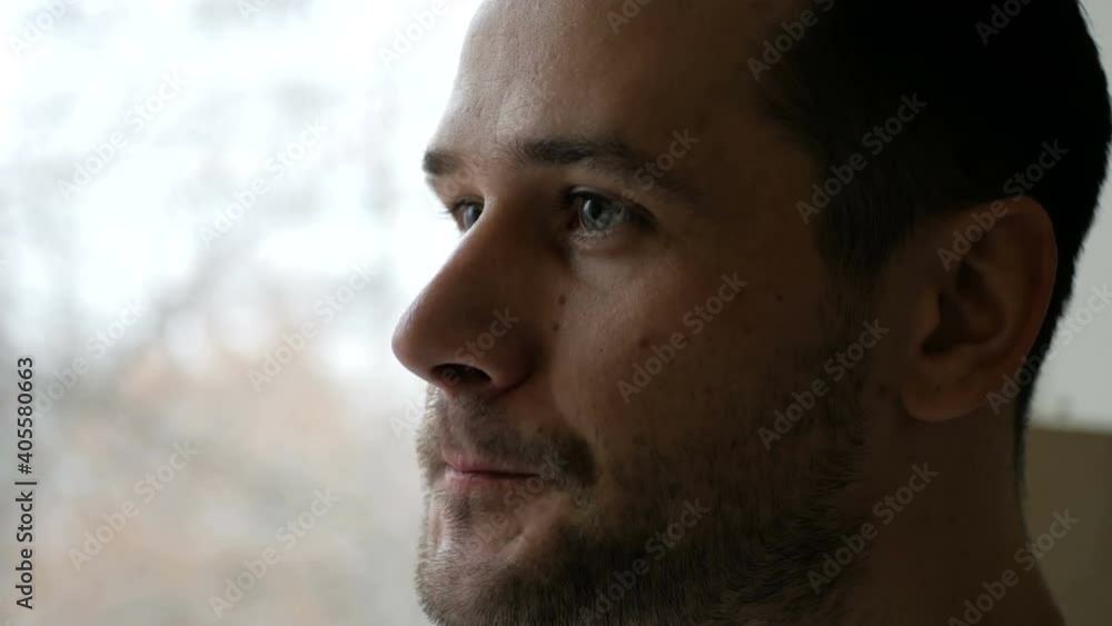 Close-up of a young man standing in his kitchen drinking coffee from a white cup. A young attractive man drinking coffee from a white cup and looking out the window. Close-up of a young man standing in his kitchen drinking coffee from a white cup. A young attractive man drinking coffee from a white cup and looking out the window.