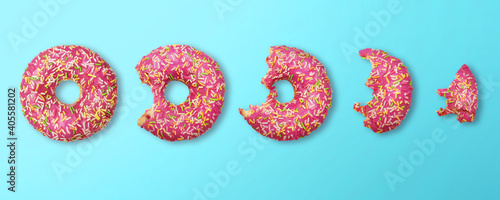 whole donut and half-eaten donuts with pink glaze and colored sprinkles on blue background