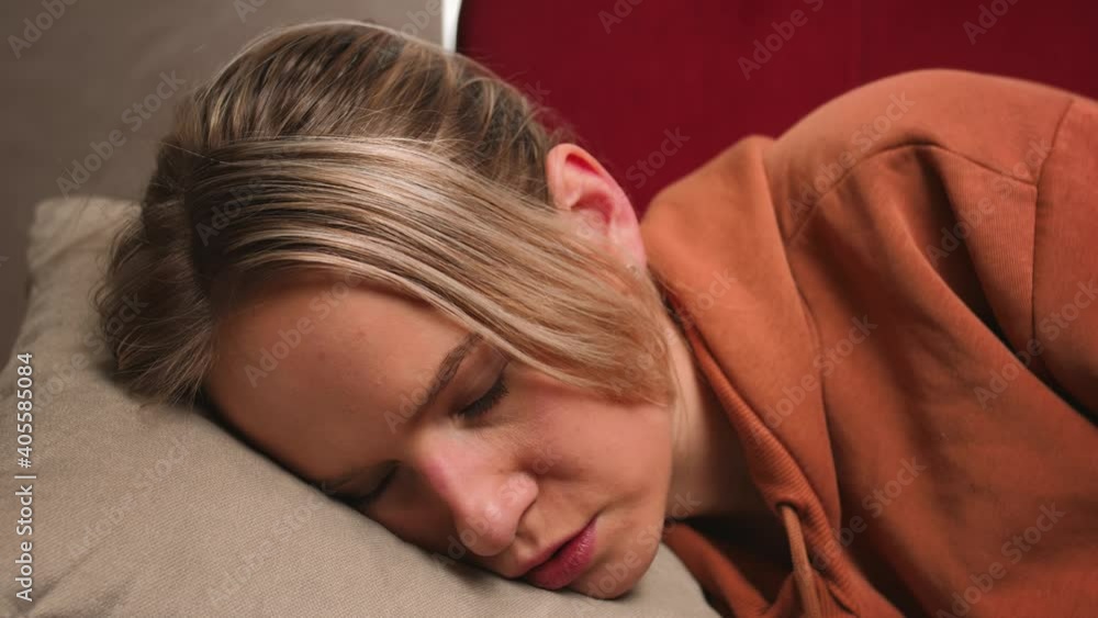 Exhausted or bored young sleepy woman falls down on sofa. Lazy housewife falls on the sofa with pillows and falls asleep Exhausted or bored young sleepy woman falls down on sofa. Lazy housewife falls on the sofa with pillows and falls asleep