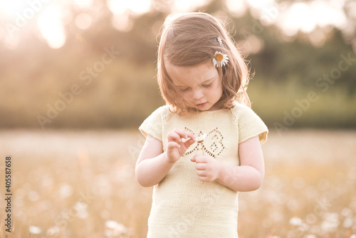 Cute funny baby girl 2-3 year old in camomila field with flowers outdoors. Summer time. Childhood.