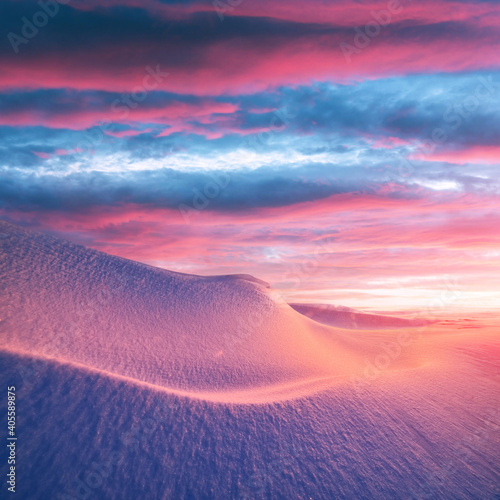 Fantastic winter landscape in snowy mountains glowing by morning sunlight. Dramatic wintry scene with frozen snowy hills at sunrise. Christmas holiday background