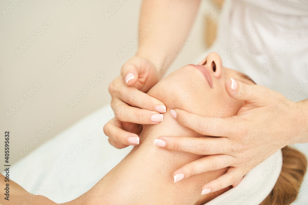 Face massage at spa salon. Doctor hands. Pretty female patient. Beauty treatment. Healthy skin procedure. Young woman head. Light background. Scrub rejuvenation. Facial dermatology mask. Detox therapy