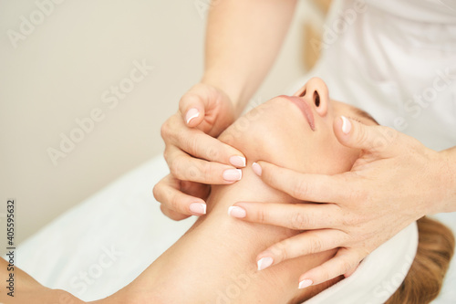 Face massage at spa salon. Doctor hands. Pretty female patient. Beauty treatment. Healthy skin procedure. Young woman head. Light background. Scrub rejuvenation. Facial dermatology mask. Detox therapy