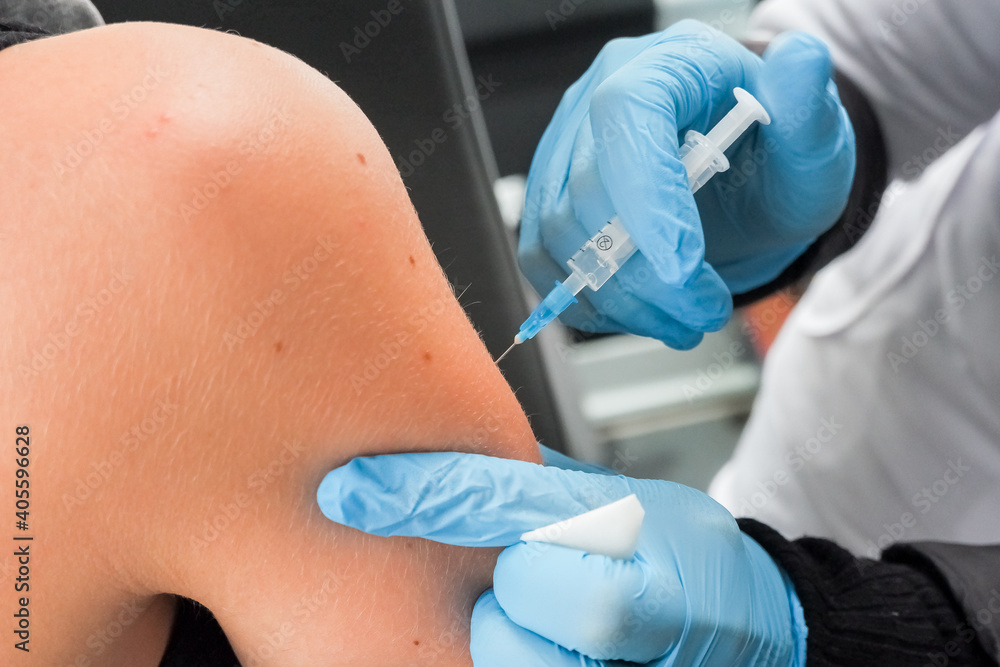 Fototapeta premium Close-up hands,nurses are vaccinations to patients using the syringe.Doctor vaccinating women in hospital.Hand in a blue glove holding syringe give injection in shoulder, arm.