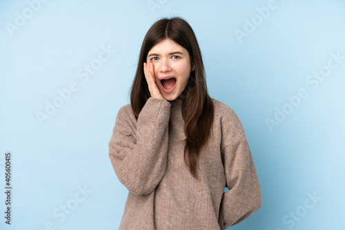 Young Ukrainian teenager girl wearing a sweater over isolated blue background with surprise and shocked facial expression