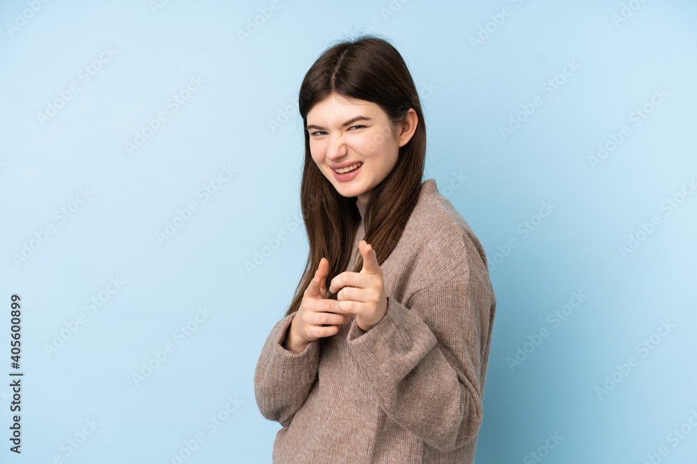 Young Ukrainian teenager girl wearing a sweater over isolated blue background pointing to the front and smiling Young Ukrainian teenager girl wearing a sweater over isolated blue background pointing to the front and smiling