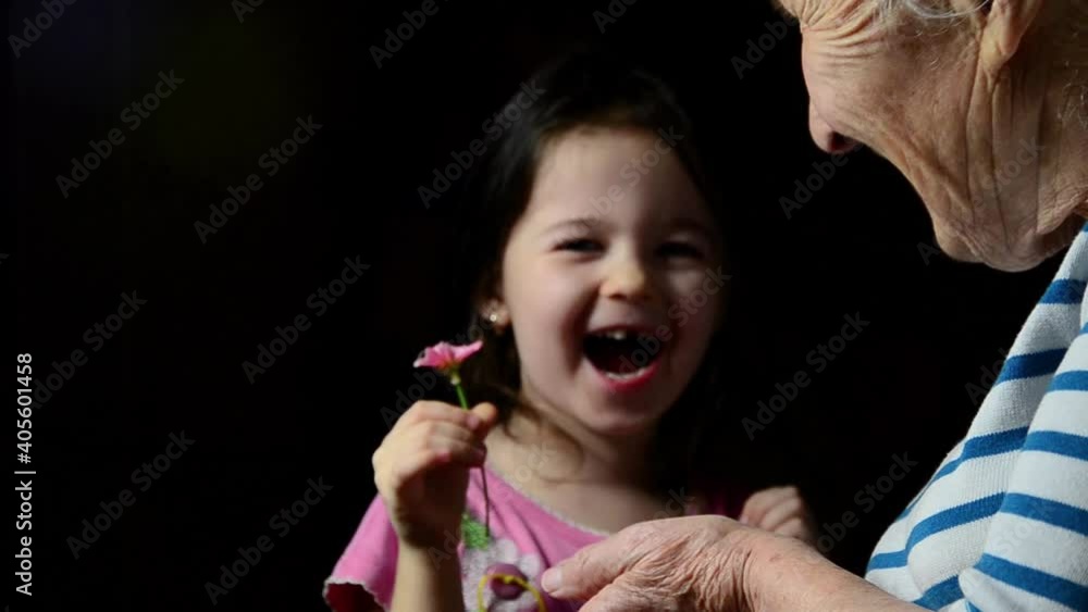 Happy child holding flowers. Joyful child congratulates grandmother on mother's day. Flowers in old wrinkled hands and hands of a child close-up. Mothers Day. Goodness and happiness concept Happy child holding flowers. Joyful child congratulates grandmother on mother's day. Flowers in old wrinkled hands and hands of a child close-up. Mothers Day. Goodness and happiness concept