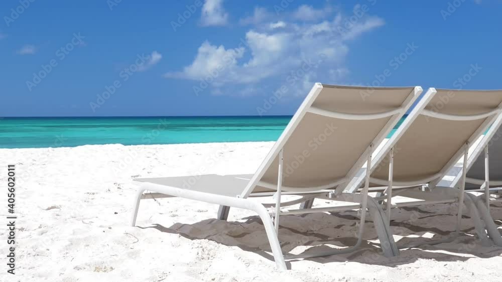 Beach scene with sunbeds close to Caribbean sea with azure water. Tropical island with sunbeds on white sandy shore Beach scene with sunbeds close to Caribbean sea with azure water. Tropical island with sunbeds on white sandy shore