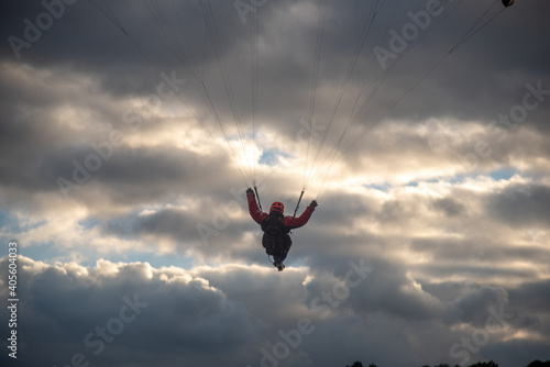 Gente haciendo parapente en un acantilado con la playa debajo y un atardecer  photo